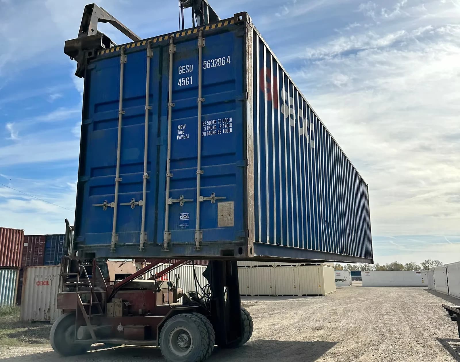 Shipping containers lifted by a container handler in the yard