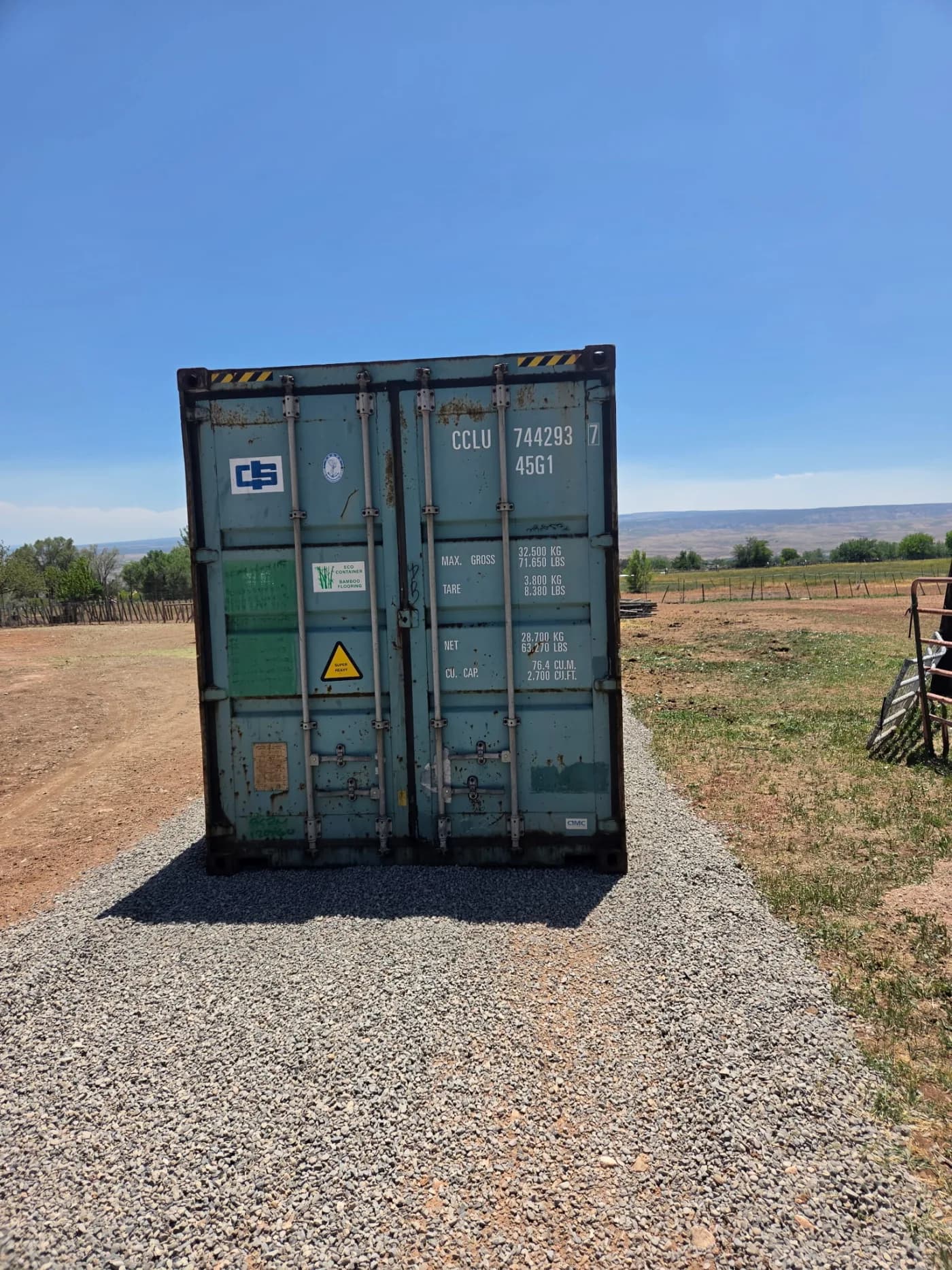 Shipping container sitting on a rock and gravel pad